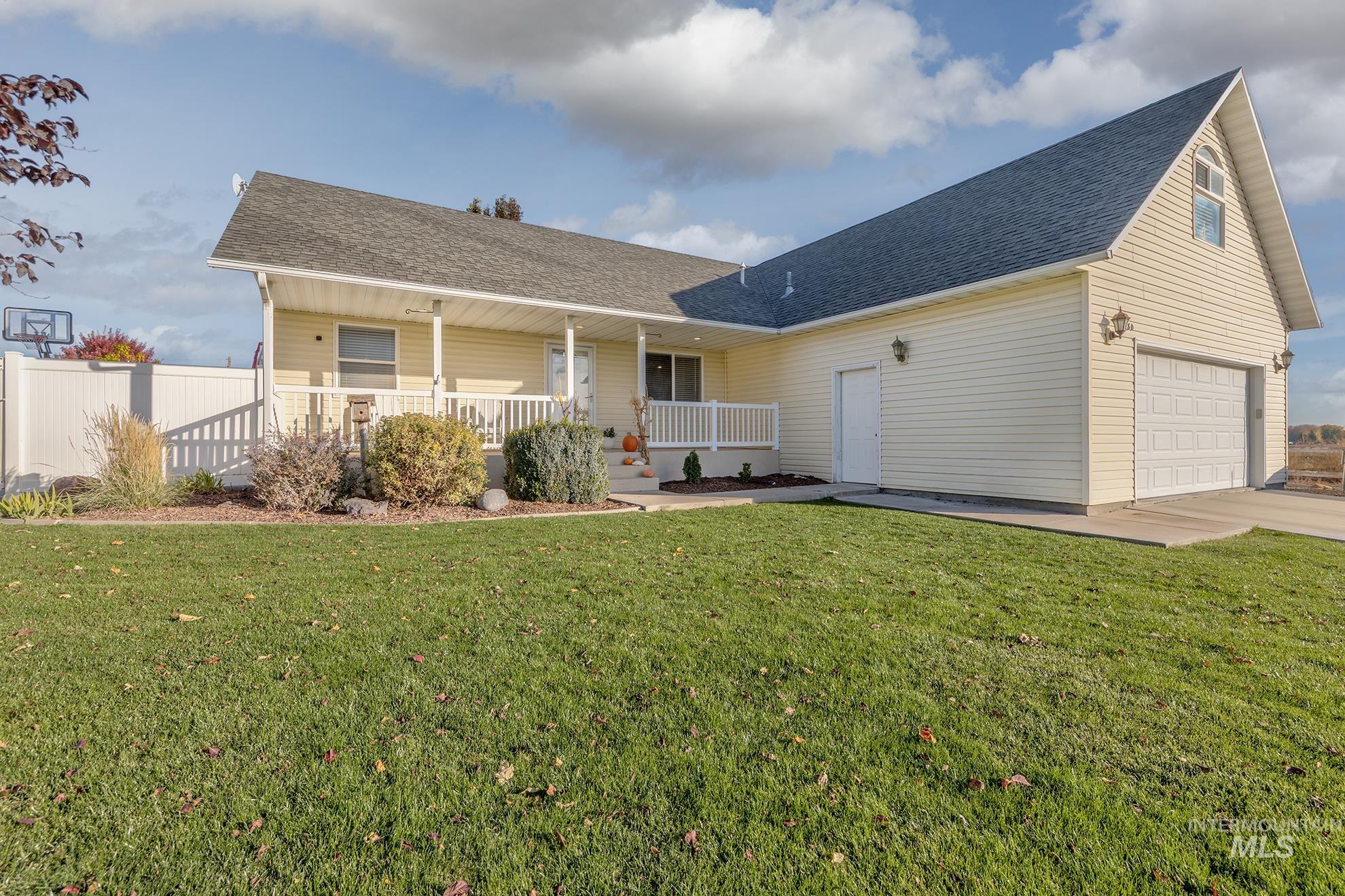 View of front of house with covered porch, a shingled roof, a front lawn, and driveway