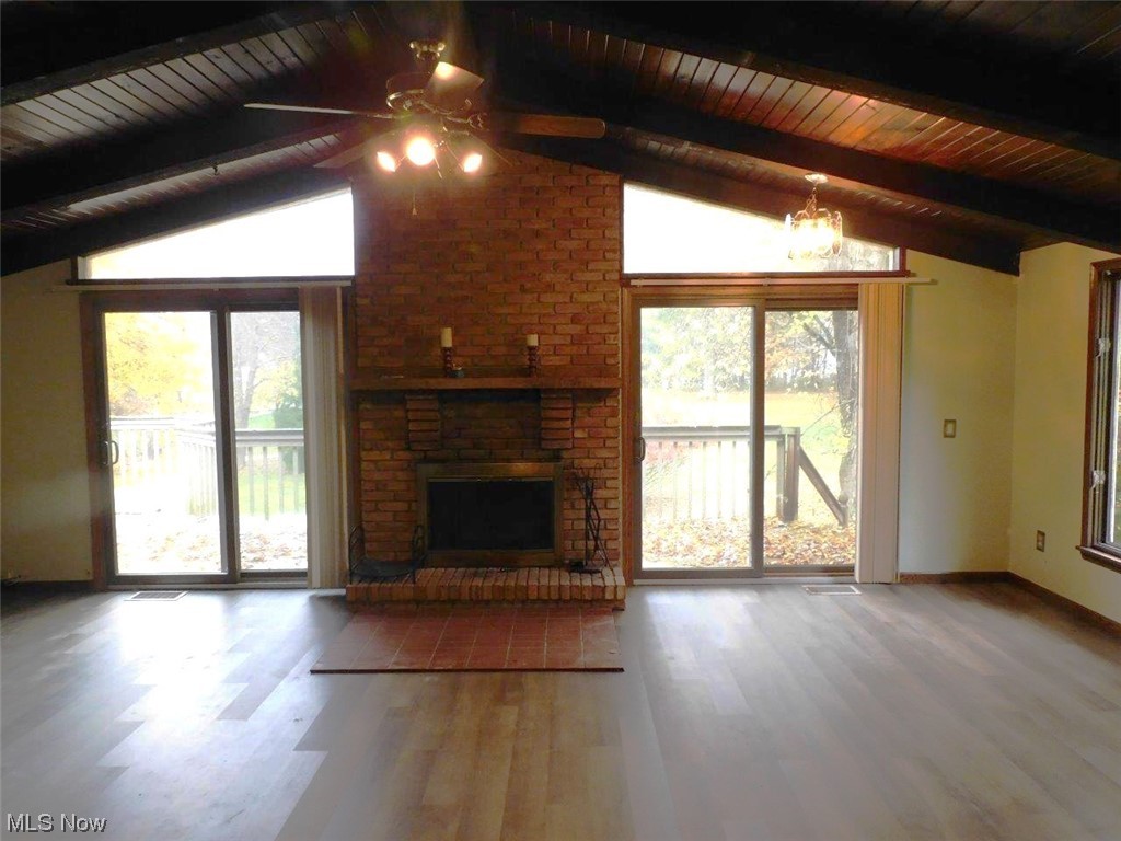 1102 Fiesta Road Southwest Dellroy, OH 44620 - Photo 8 of 20 Unfurnished living room with ceiling fan with notable chandelier, vaulted ceiling with beams, and a wealth of natural light