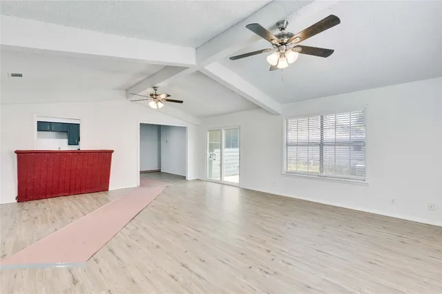 a view of an empty room with window and a ceiling fan