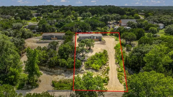 an aerial view of residential house with outdoor space and trees all around