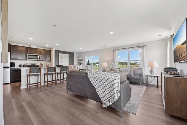 a living room with furniture kitchen view and a wooden floor