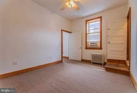 an empty room with a ceiling fan and window