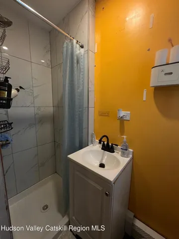 a bathroom with a sink and mirror with shower