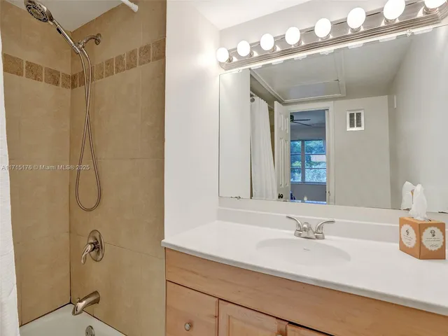 a bathroom with a granite countertop sink a mirror and shower