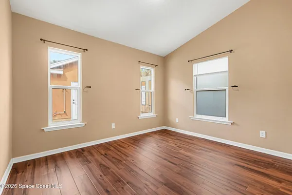 an empty room with wooden floor and windows