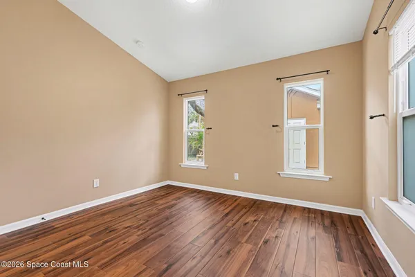 an empty room with wooden floor and windows