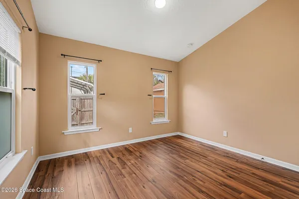 an empty room with wooden floor and windows