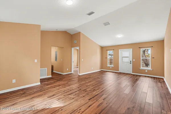 a view of an empty room with wooden floor and a window