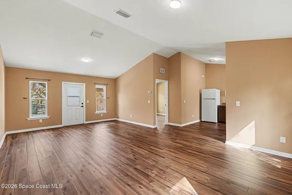 a view of an empty room with window and wooden floor