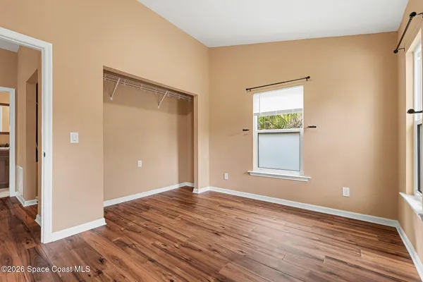 a view of an empty room with wooden floor and a window
