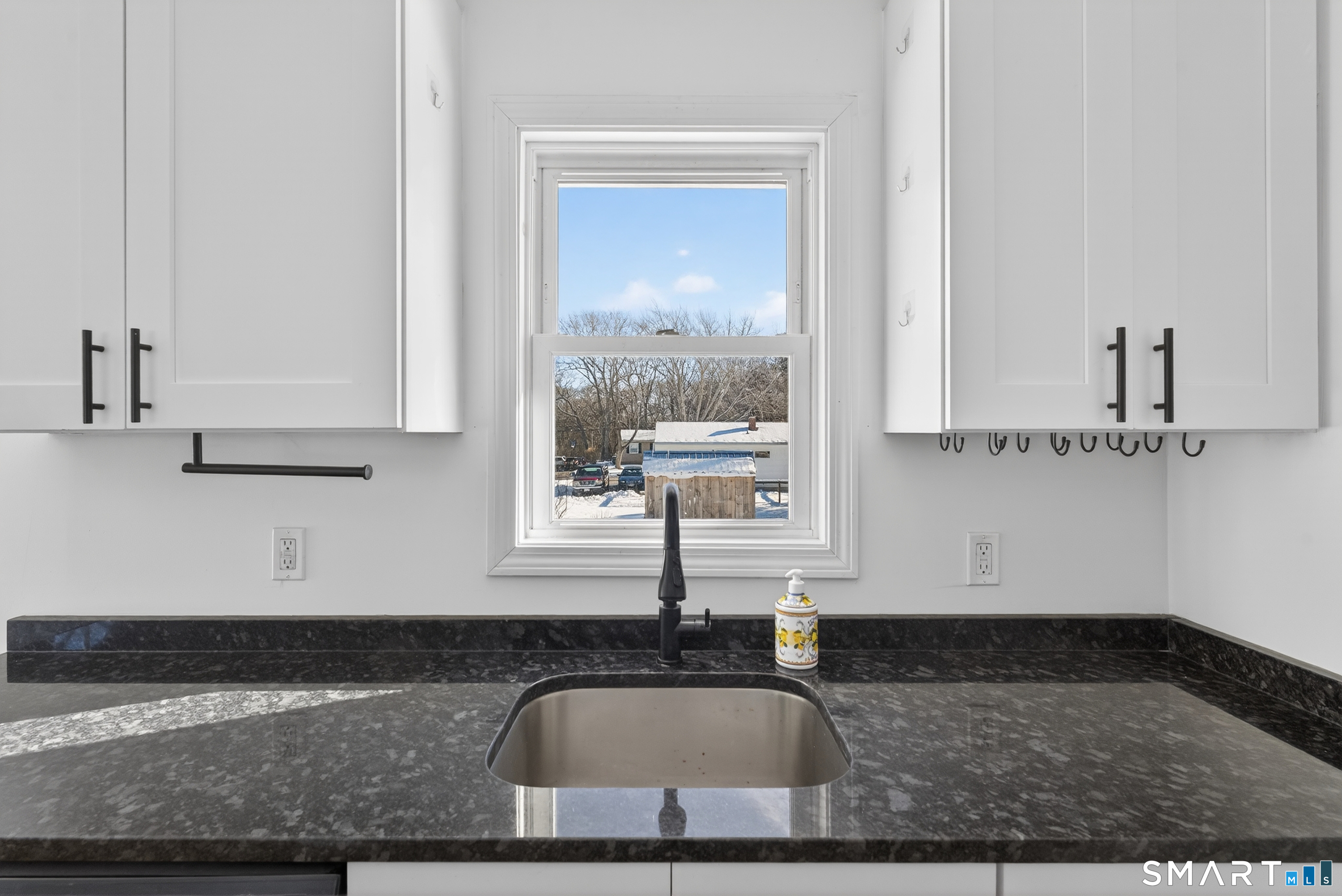 a kitchen with granite countertop a sink and white cabinets