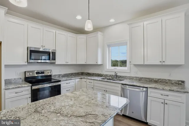 a kitchen with granite countertop a sink a stove and microwave