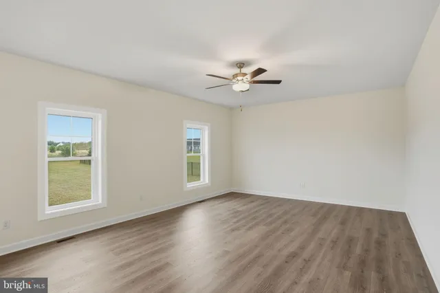 a view of an empty room with a window and wooden floor