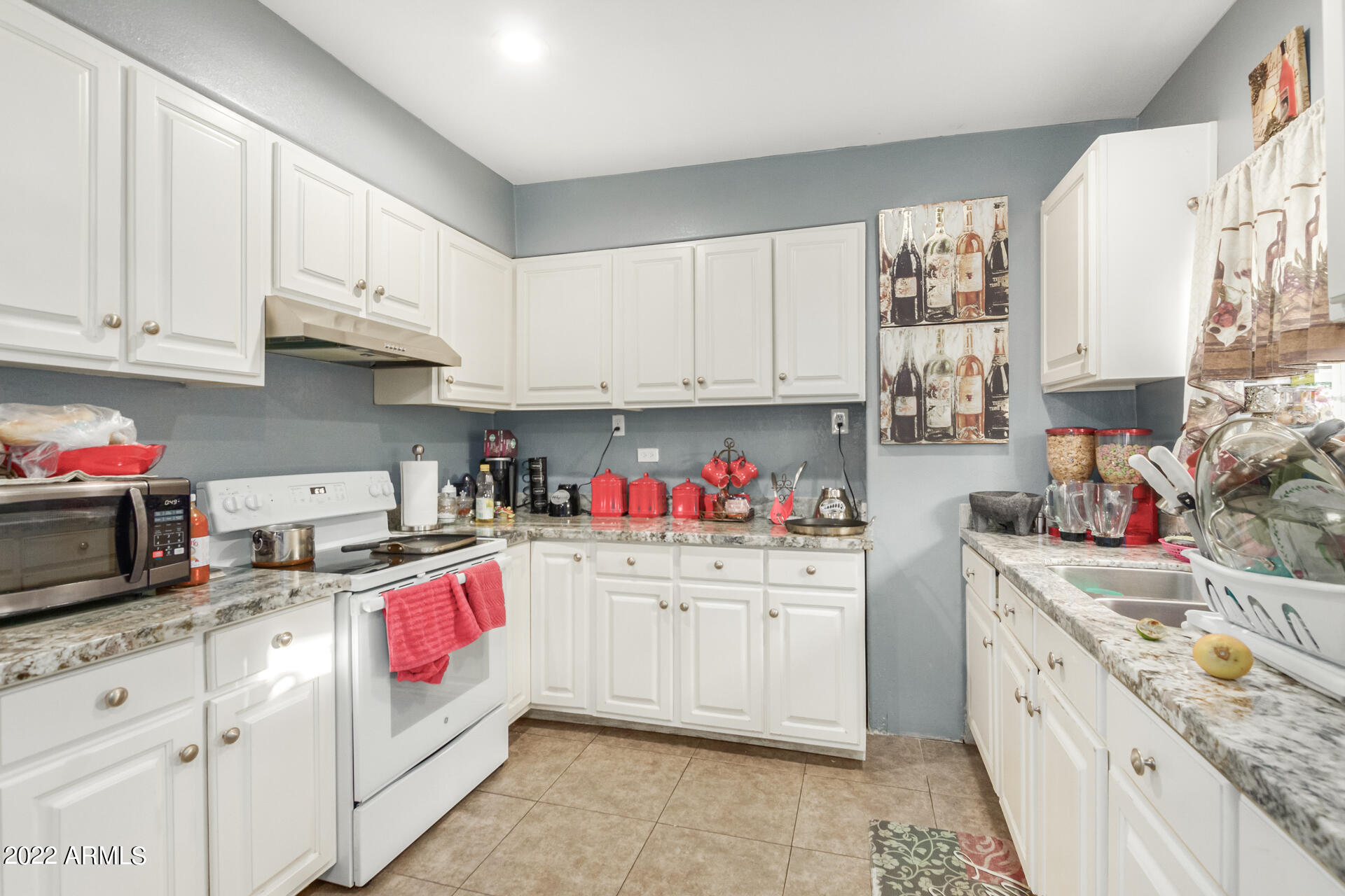 2726 West Taylor Street Phoenix, AZ 85009 - Photo 18 of 26 a kitchen with kitchen island granite countertop white cabinets and white appliances