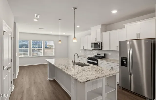 a kitchen with granite countertop kitchen island stainless steel appliances a refrigerator a stove a sink a dining table and chairs