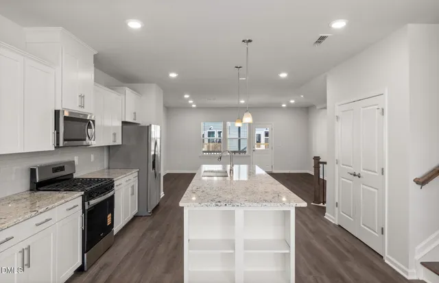 a kitchen with a refrigerator a stove top oven a sink dishwasher and white cabinets with wooden floor