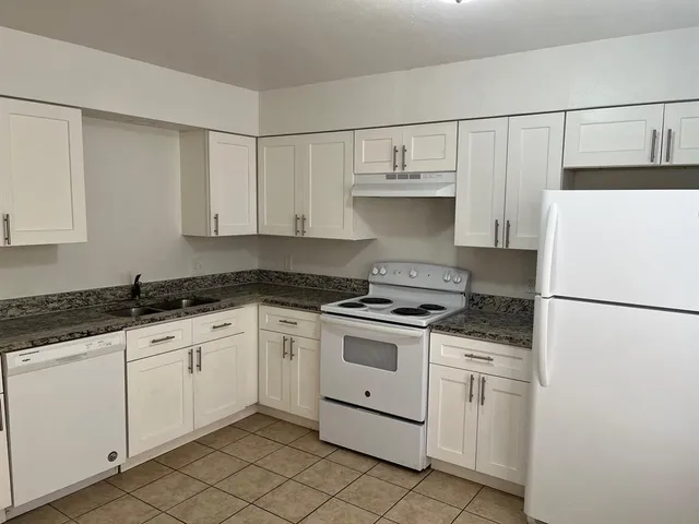 a kitchen with white cabinets and white appliances