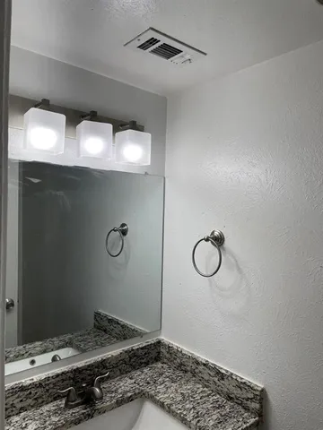 a bathroom with a granite countertop sink and a mirror