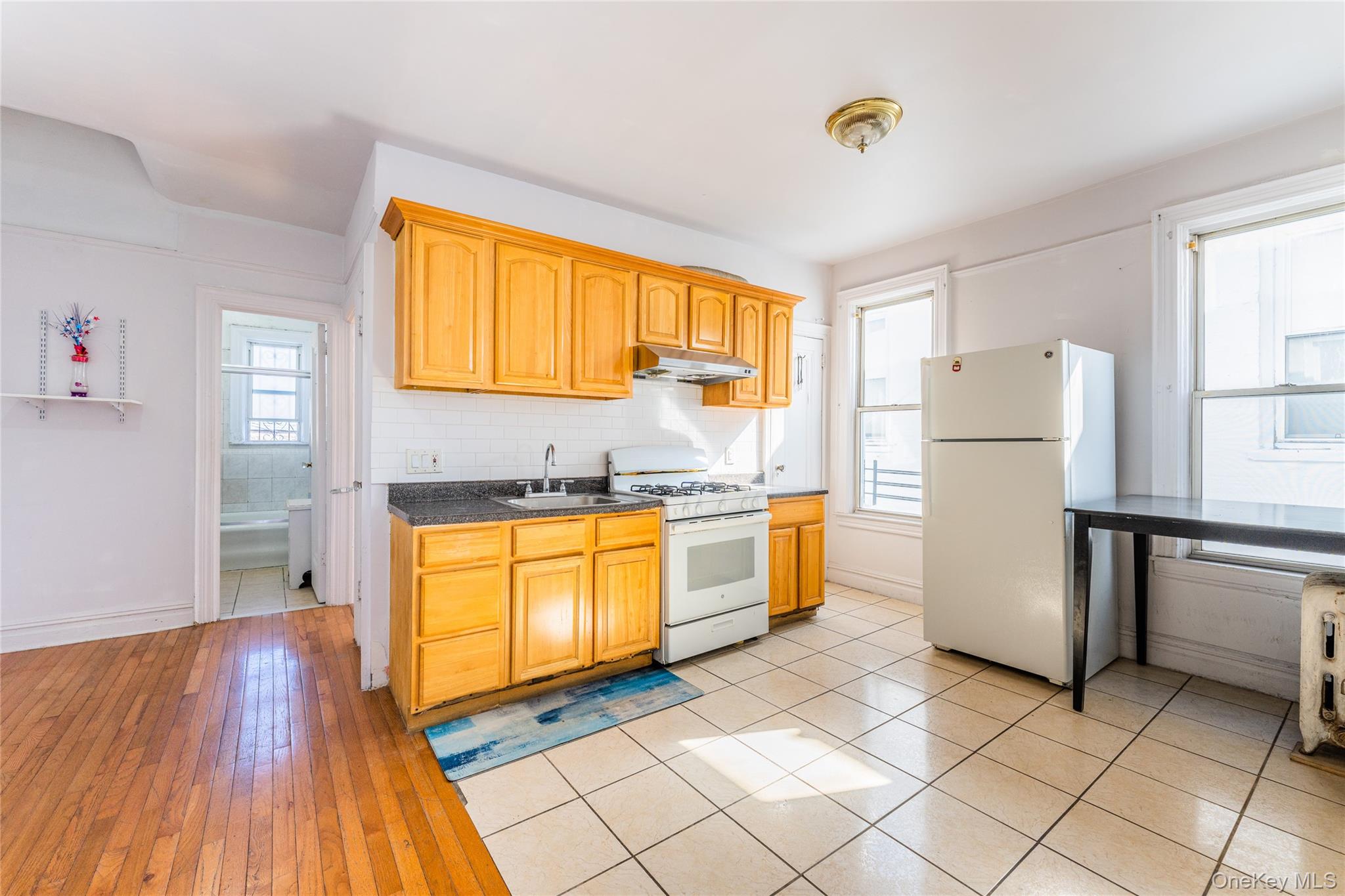 31-39 84th Street Queens, NY 11370 - Photo 15 of 29 a kitchen with a refrigerator and wooden cabinets