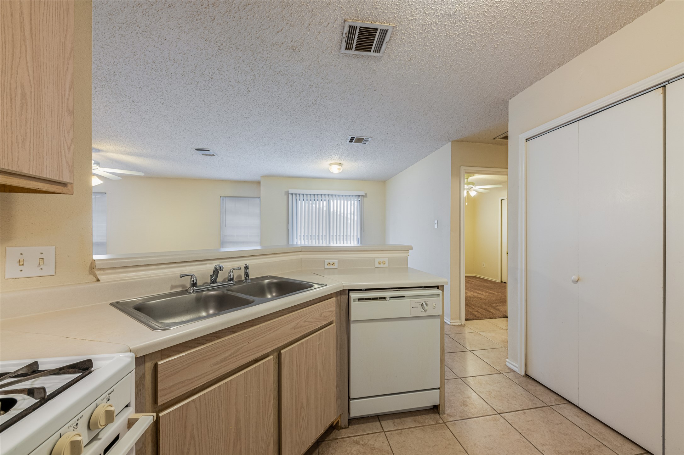 7216 Aldea Drive, Unit A Austin, TX 78745 - Photo 12 of 25 Kitchen featuring a double stainless steel sink, light-toned cabinetry, light-colored countertops, a built-in dishwasher, and tile flooring