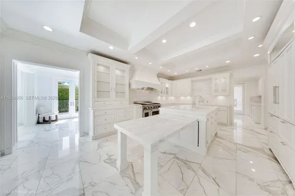 a large white kitchen with lots of counter space and windows