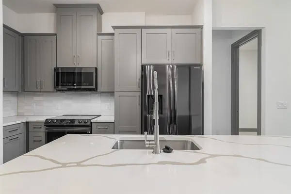 a kitchen with stainless steel appliances kitchen island granite countertop a refrigerator and a stove top oven