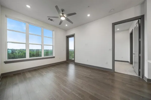 an empty room with wooden floor fan and windows