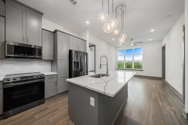 a kitchen with stainless steel appliances kitchen island granite countertop a sink and dishwasher a refrigerator with wooden floor