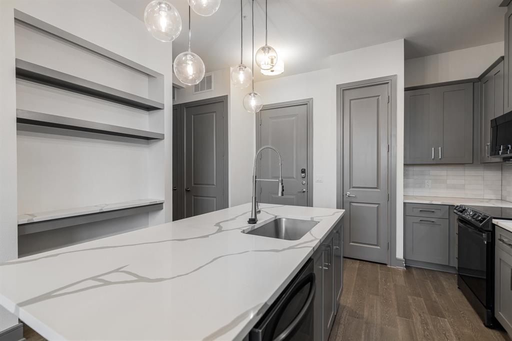 2700 Old Denton Road, Unit 3336 Carrollton, TX 75007 - Photo 8 of 28 a kitchen with stainless steel appliances kitchen island granite countertop a sink and dishwasher a refrigerator with wooden floor