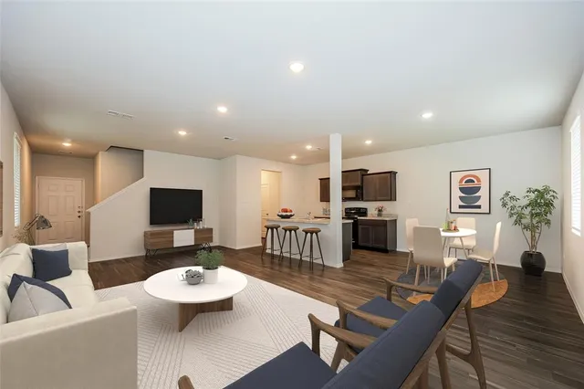 a living room with furniture kitchen view and a wooden floor