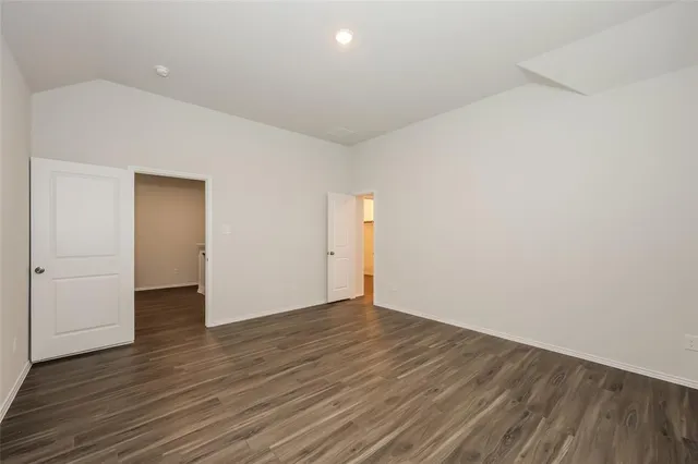 a view of an empty room with wooden floor and closet