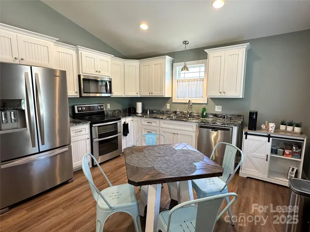 a kitchen with stainless steel appliances granite countertop a stove a sink a microwave a dining table and chairs