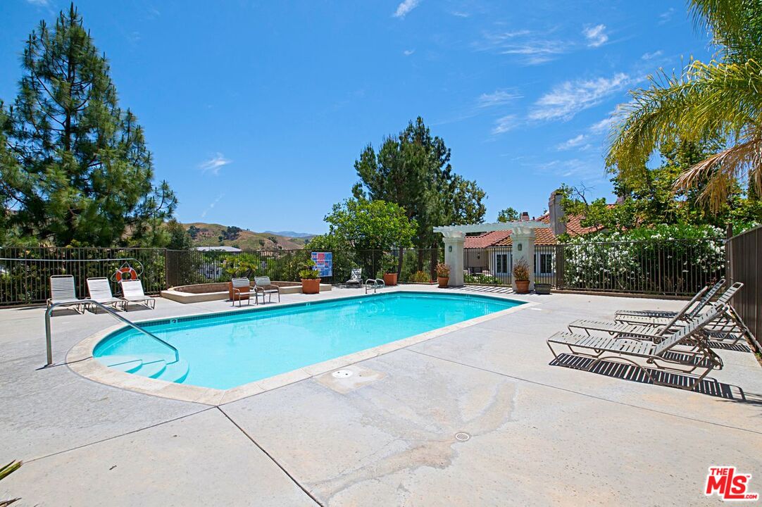 4240 Lost Hills Road, Unit 2602 Calabasas, CA 91301 - Photo 33 of 38 a view of a swimming pool with a lounge chair and palm trees