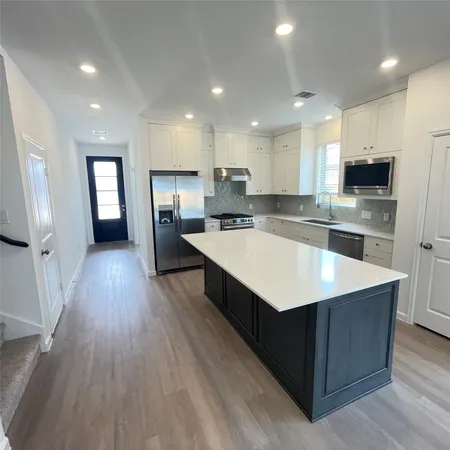 a kitchen with kitchen island a sink dishwasher stove and wooden floor