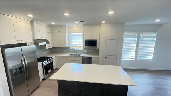 a large kitchen with stainless steel appliances kitchen island granite countertop a stove a sink a refrigerator and white cabinets