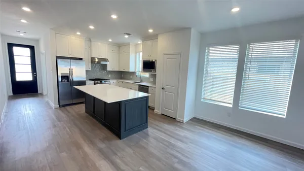 a kitchen with kitchen island wooden floors appliances and cabinets