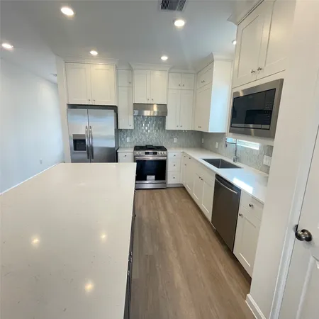 a large kitchen with stainless steel appliances granite countertop a stove a sink and a refrigerator