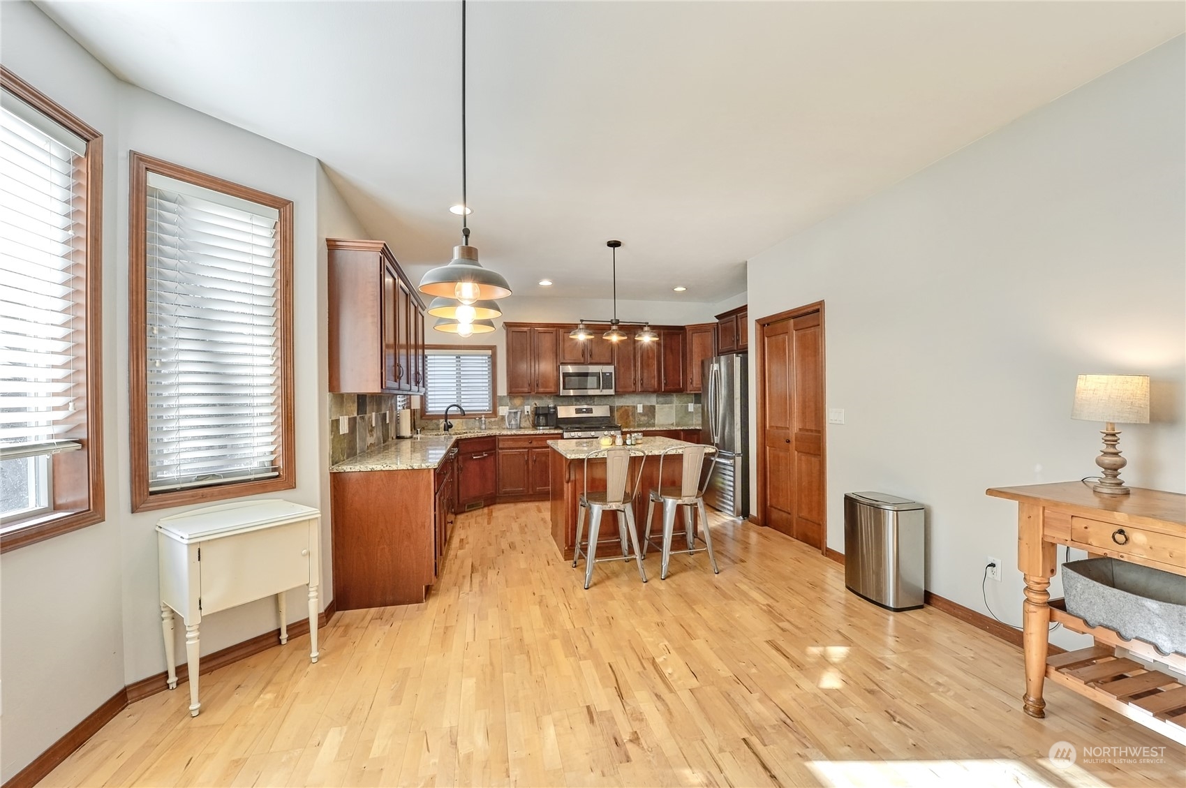5576 Old Settler Drive Ferndale, WA 98248 - Photo 7 of 20 a dining room with stainless steel appliances kitchen island granite countertop a refrigerator a stove a dining table and chairs with wooden floor