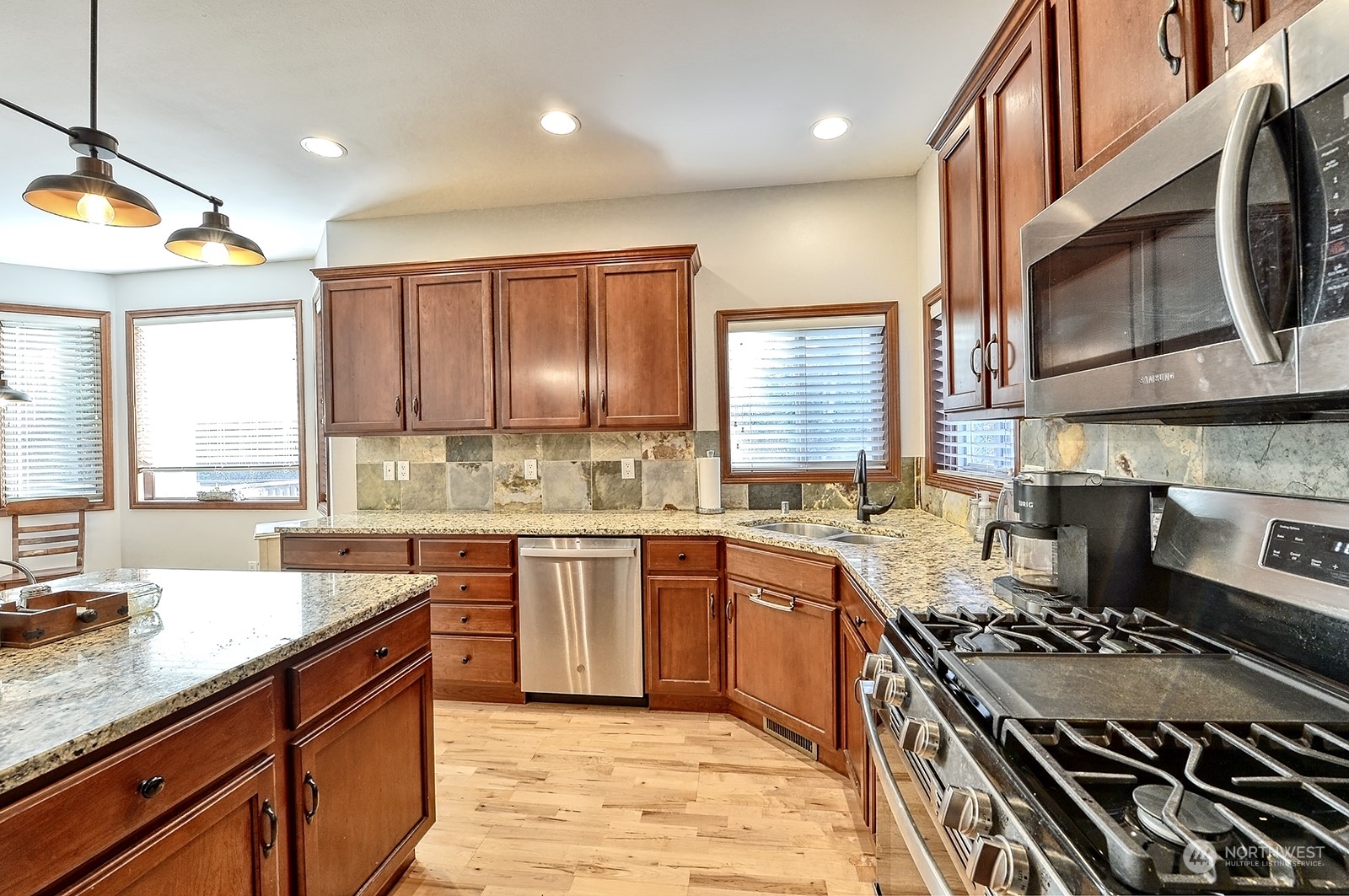 5576 Old Settler Drive Ferndale, WA 98248 - Photo 9 of 20 a kitchen with stainless steel appliances granite countertop a stove a sink dishwasher and a microwave oven with large wooden cabinets