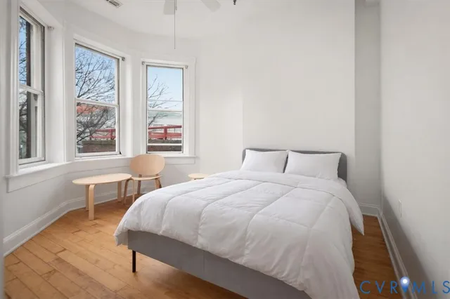 a bedroom with a bed a table and windows