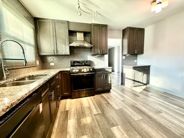 a kitchen with stainless steel appliances granite countertop a stove a sink and a microwave