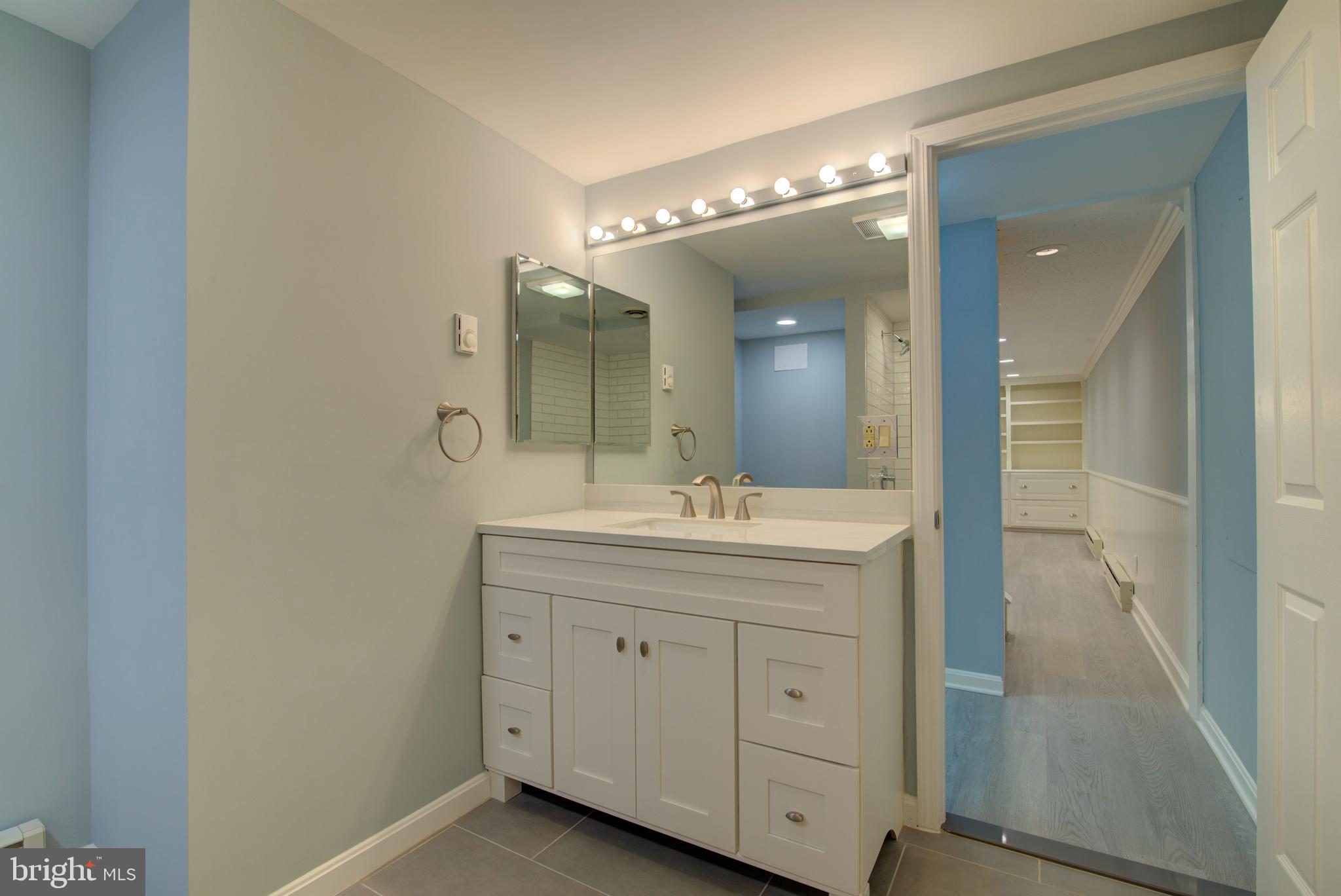10405 Trumpeter Court Vienna, VA 22182 - Photo 30 of 43 a spacious bathroom with a granite countertop sink a mirror and a shower