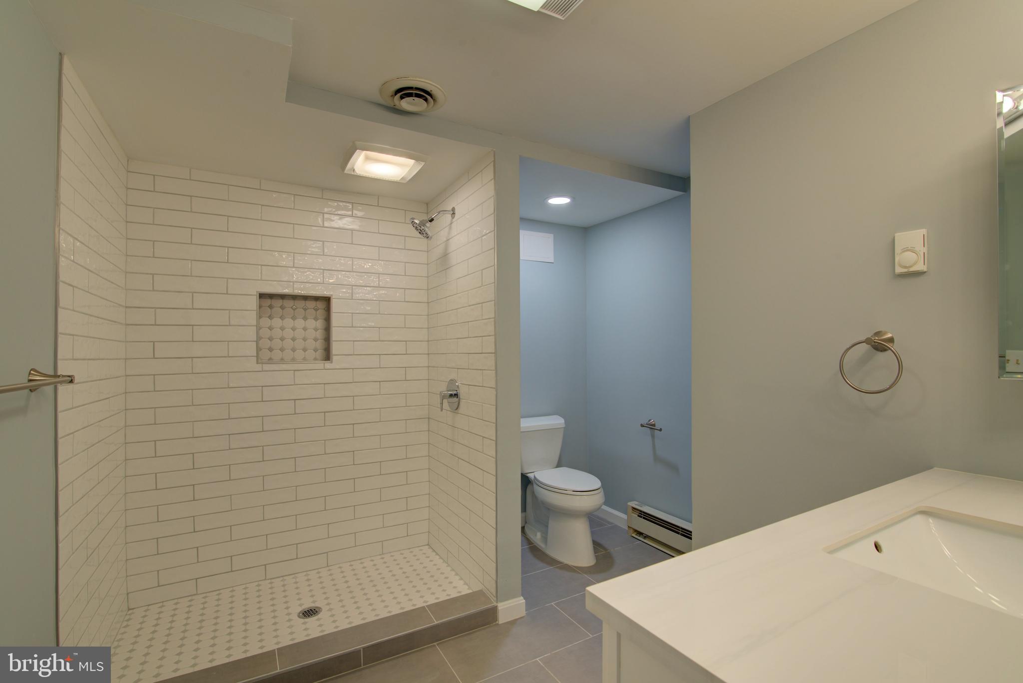 10405 Trumpeter Court Vienna, VA 22182 - Photo 31 of 43 a bathroom with a granite countertop sink a toilet and shower