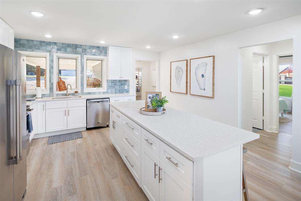 1907 Buck Run Graford, TX 76449 - Photo 9 of 33 a large kitchen with granite countertop a stove a sink a refrigerator and white cabinets with wooden floor