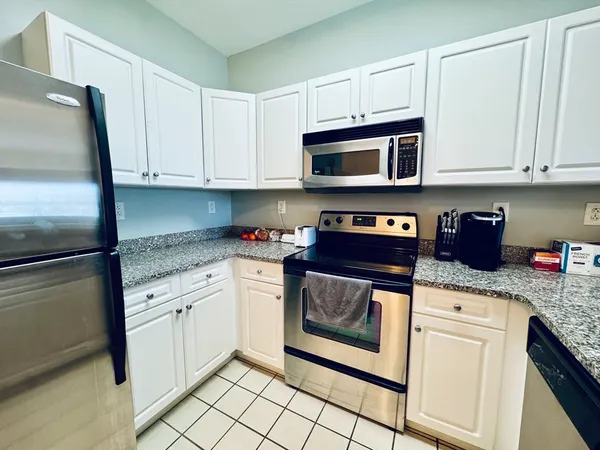 a kitchen with cabinets stainless steel appliances granite countertop a stove a sink and a microwave