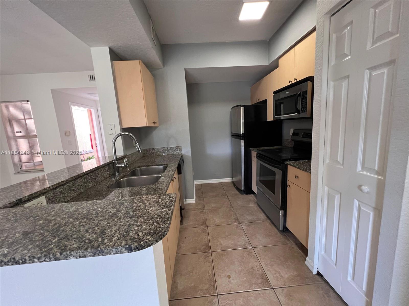 2400 Centergate Drive, Unit 102 Miramar, FL 33025 - Photo 2 of 12 a kitchen with stainless steel appliances granite countertop a sink stove and refrigerator
