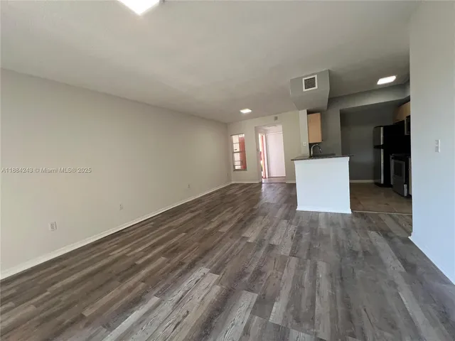 a view of kitchen and empty room with wooden floor