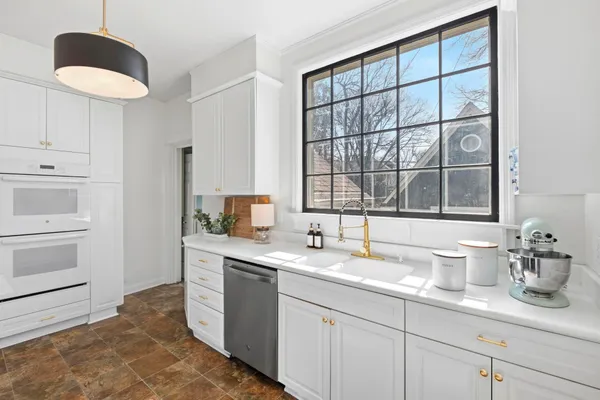 a kitchen with stainless steel appliances granite countertop a refrigerator a stove a sink and white cabinets with wooden floor