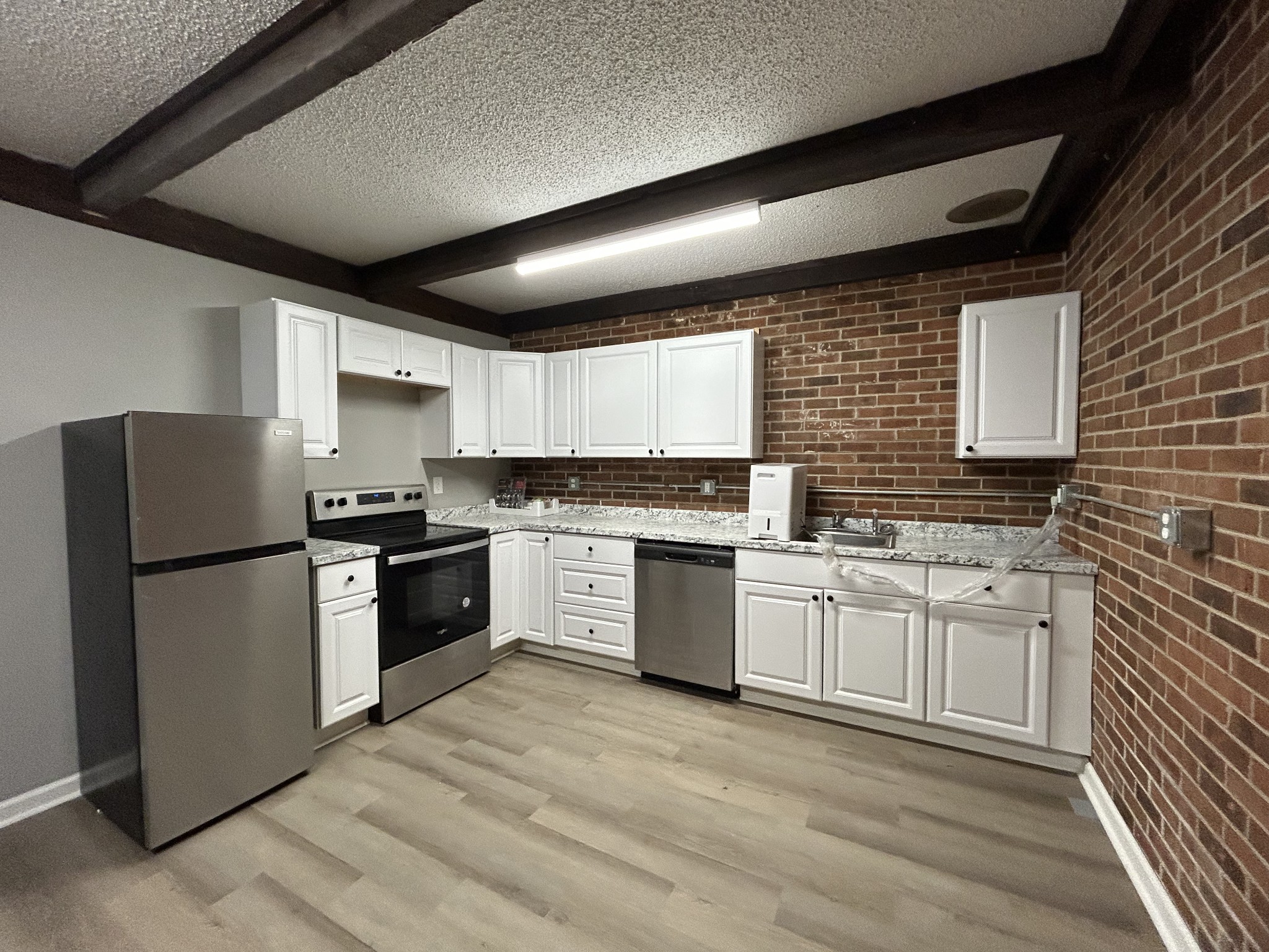 a kitchen with granite countertop a refrigerator stove top oven and sink
