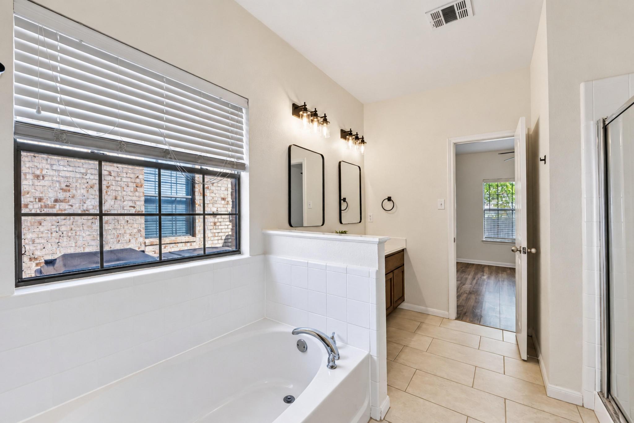 150 Engineers Pass Jarrell, TX 76537 - Photo 33 of 40 Tile flooring and a deep soaking tub anchor this bright primary bathroom layout.